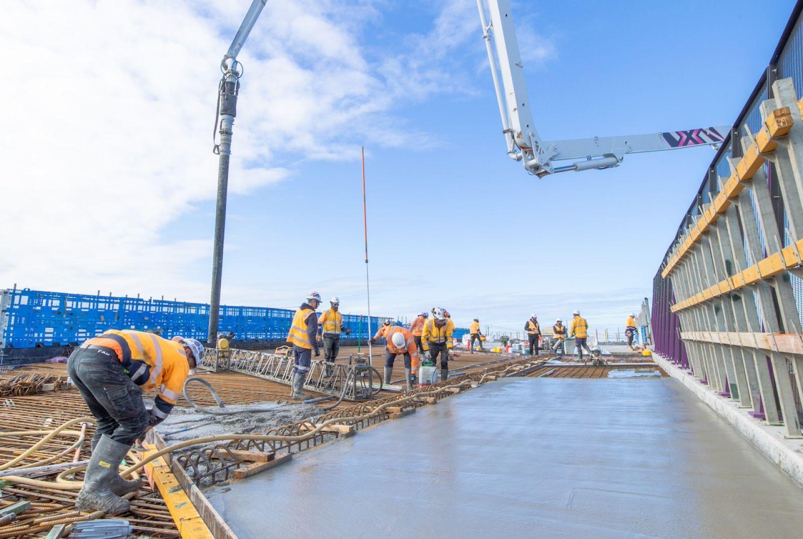 Commercial construction crew placing and finishing concrete during a monitored slab pour.